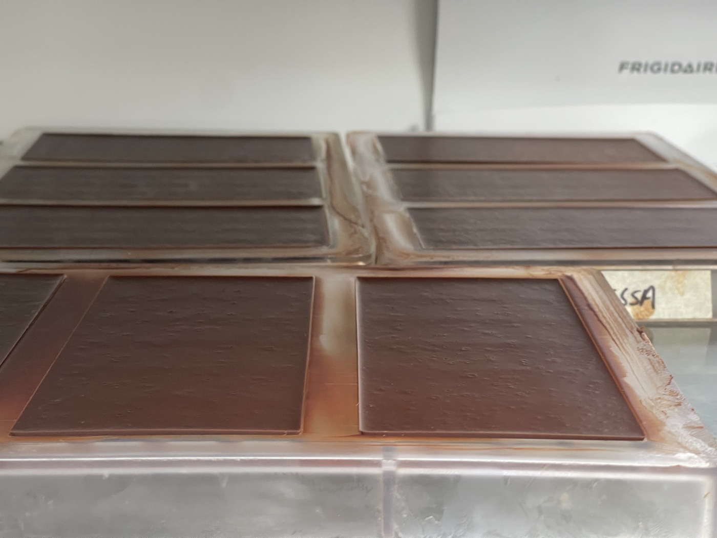 Tempered chocolate bars setting in moulds in the fridge