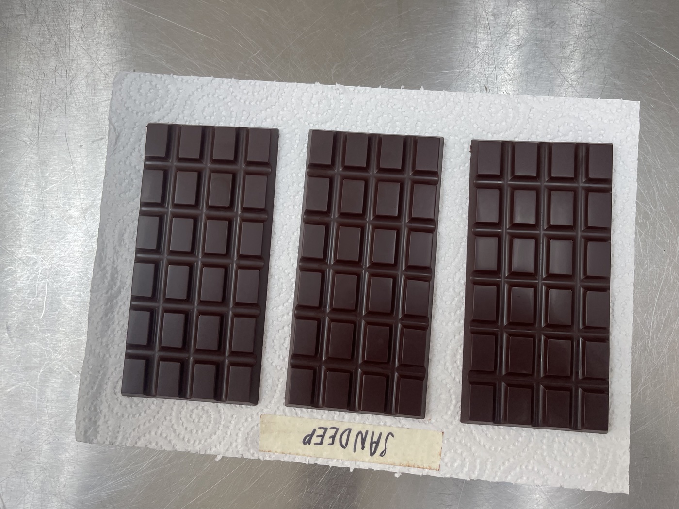 Three finished dark chocolate bars labelled Sandeep